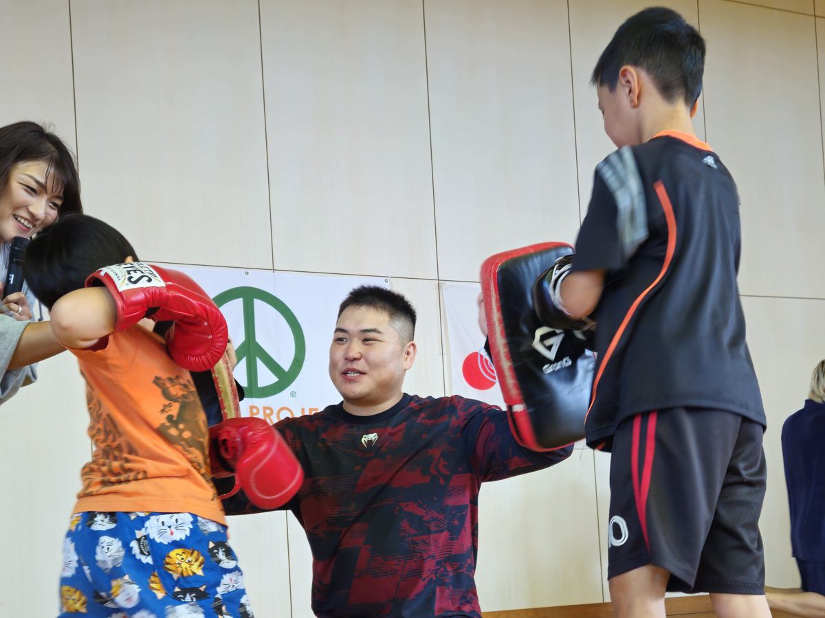 格闘技レッスン。参加選手がミットを構え、子どもたちがパンチを打ち込みました。