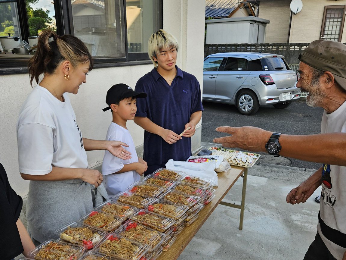 出来上がった焼きそばを地域の皆さまに手渡すRENA選手と鶴屋怜選手。